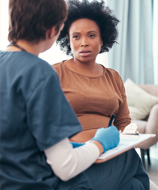 Pregnant african american woman with healthcare professional taking notes.