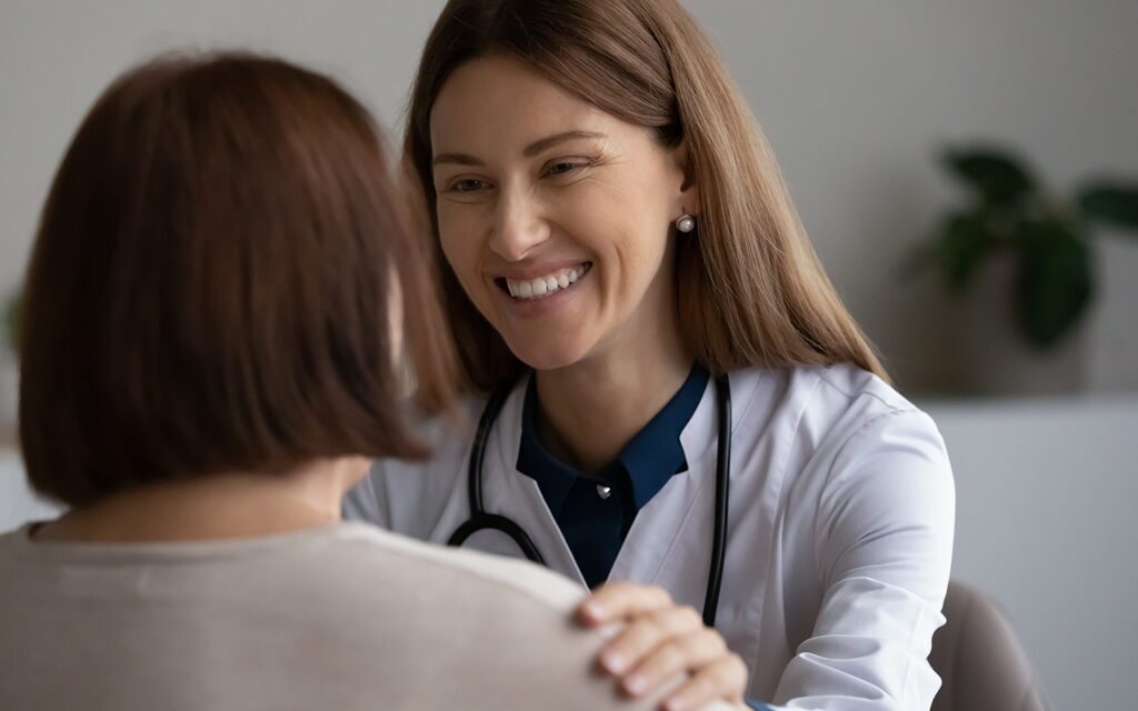 smiling female doctor with hand on patient's shoulder.