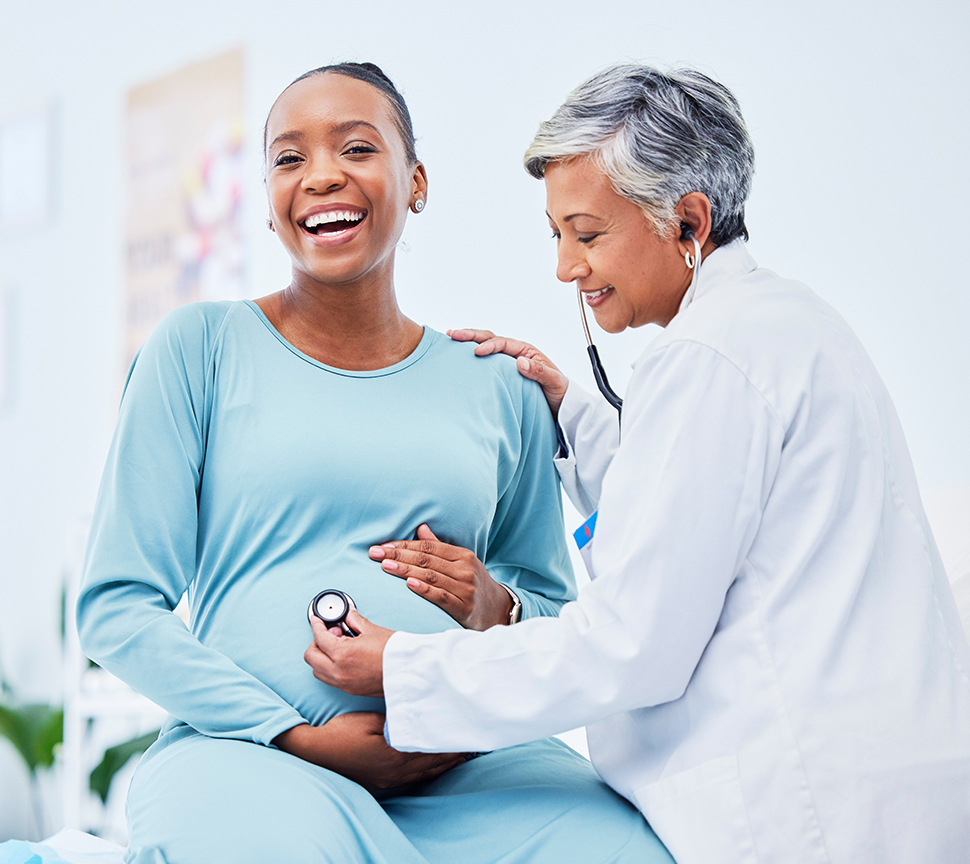 female doctor using stethoscope to listen to pregnant woman's stomach area.